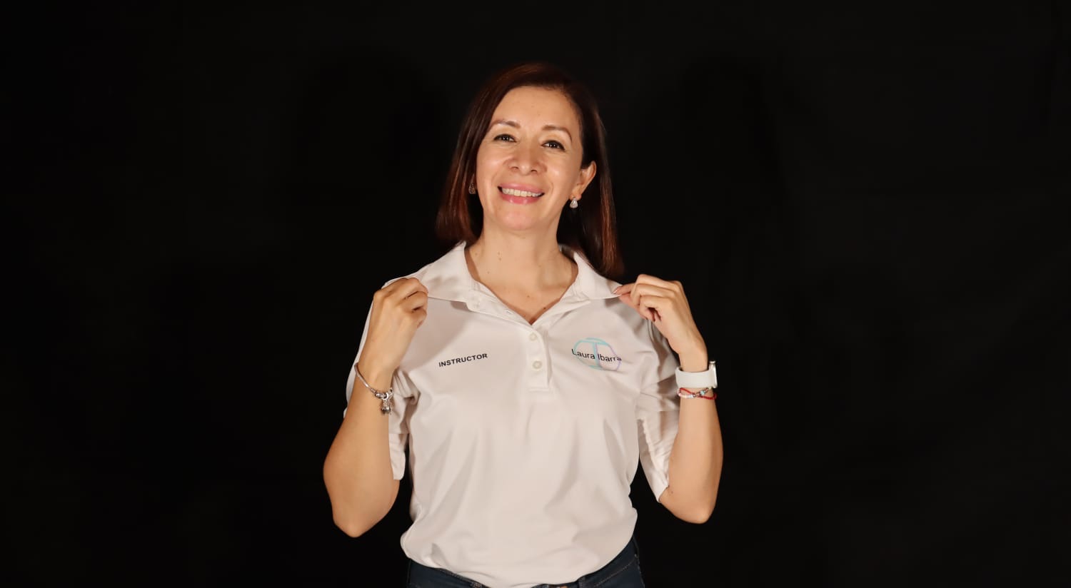 Ary Solís como instructora certificada, sonriendo, con polo de instructor sobre fondo oscuro
